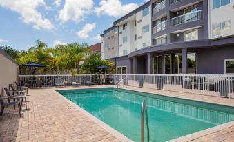 a large swimming pool is surrounded by a brick patio and a building with a balcony at Courtyard Tampa Oldsmar