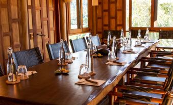 a long wooden dining table with chairs arranged around it , ready for a group of people to sit and eat at Soneva Kiri