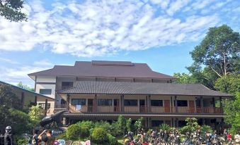 a large building with a sloping roof is surrounded by trees and parked motorcycles in front of it at Hugpua Hotel