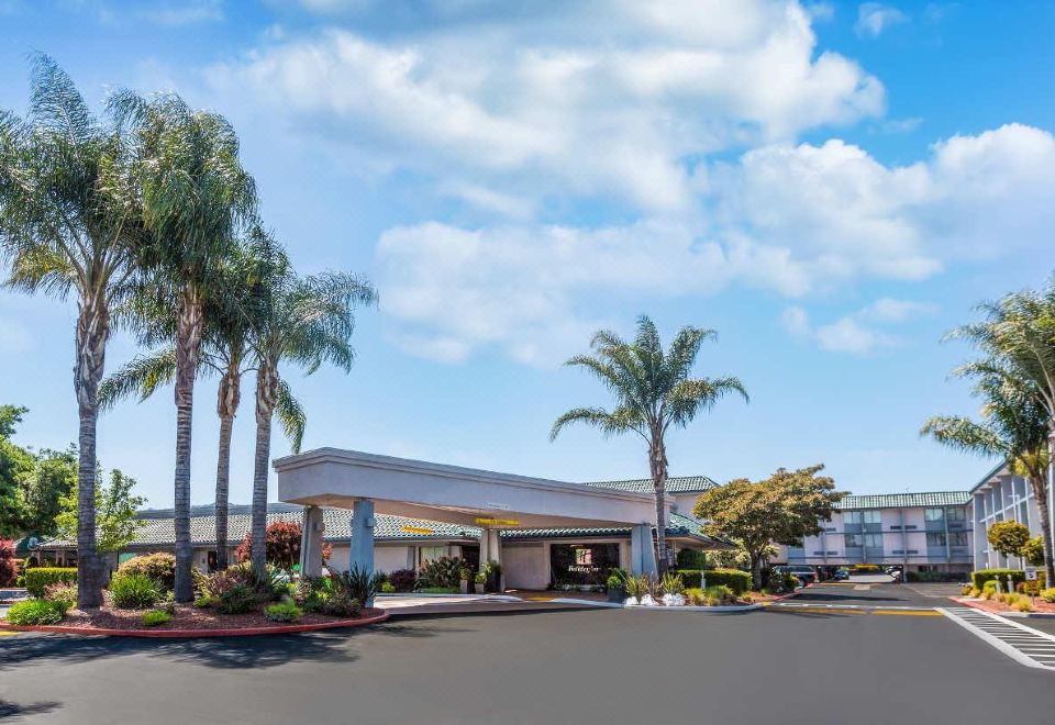 a large , modern building with palm trees and a parking lot in front of it at Holiday Inn Dublin - Pleasanton, an IHG Hotel