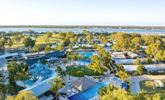 aerial view of a large resort with multiple pools and water slides , surrounded by palm trees at Big4 Sandstone Point Holiday Resort Bribie Island