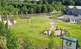 a bird 's eye view of a park with green grass , trees , and a road leading to a building at An Grianan Hotel