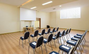 a conference room with rows of chairs arranged in a semicircle , and a projector screen mounted on the wall at Blue Bay Halkidiki