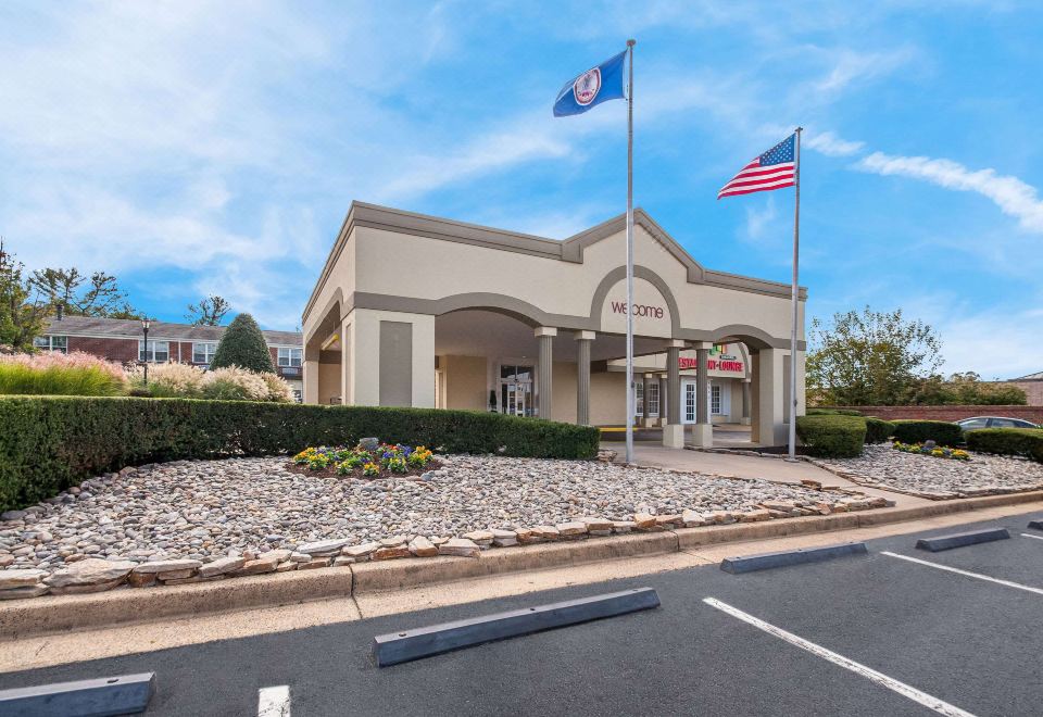 "a building with a sign that says "" the inn "" is shown with flags flying in front of it" at Clarion Inn Falls Church- Arlington