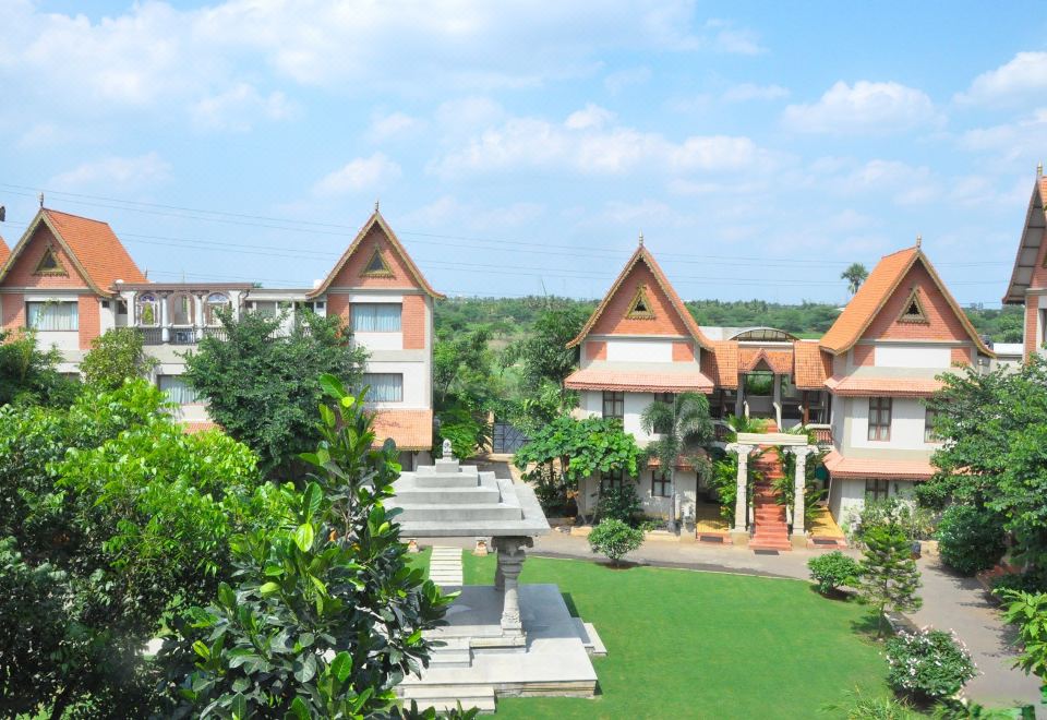 a modern residential building with a unique architectural design , surrounded by lush greenery and a traditional chinese temple at Aalankrita Resort and Convention