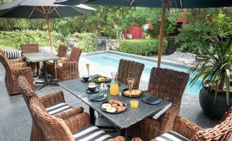 a patio set with a table and chairs , surrounded by umbrellas and overlooking a pool at Ruby Rose