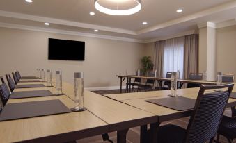 a conference room with multiple tables , chairs , and a television mounted on the wall , ready for a meeting at Hampton Inn Hallandale Beach-Aventura