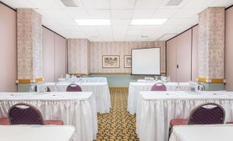 a conference room set up for a meeting , with chairs arranged in rows and a projector on the wall at Ramada by Wyndham Cumberland Downtown