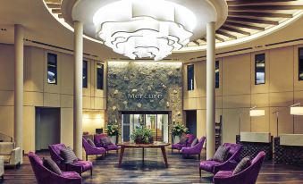 a modern , well - lit room with wooden floors and a high ceiling features purple armchairs around a wooden table at Mercure Iguazu Hotel Iru