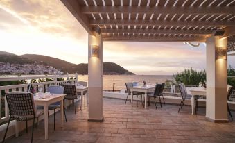 a rooftop patio with several tables and chairs , providing a pleasant outdoor dining experience for guests at Skopelos Village Hotel