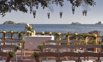 a wedding ceremony is taking place on a patio overlooking the ocean , with chairs set up for guests at Cala de Mar Resort & Spa Ixtapa