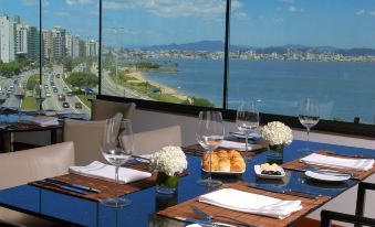 a table is set with wine glasses , plates , and a view of the ocean in a room with large windows at Majestic Palace Hotel