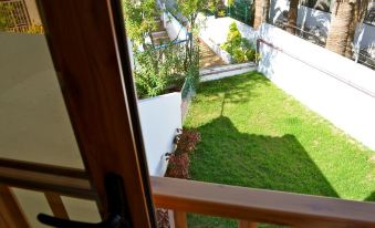 a view from an open door shows a garden and a white building with a staircase at Club Olympus in Garden City