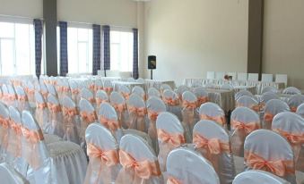 a large room filled with rows of white chairs , each adorned with an orange bow at Seulawah Grand View