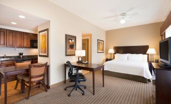 a hotel room with a king - sized bed , a desk , a chair , a tv , and a bathroom at Homewood Suites by Hilton Minneapolis-New Brighton