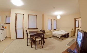 a small , well - furnished apartment with a dining table and chairs , a couch , and a television at Green Life Family Apartments Pamporovo