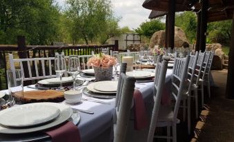 a beautifully set dining table with white plates , wine glasses , and flowers , surrounded by outdoor settings at River Rock Lodge