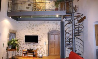 a cozy living room with a red couch , a television , and a spiral staircase leading to a loft area at Le Manoir