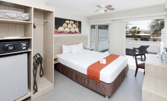 a large bed with a white and orange blanket is in a room with a sliding glass door at Casa Andina Standard Talara