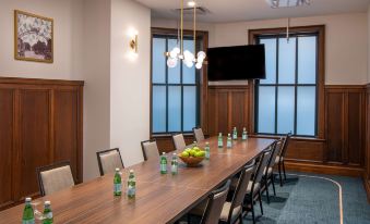 a conference room with a long wooden table , several chairs , and a television mounted on the wall at Hilton Garden Inn Flint Downtown