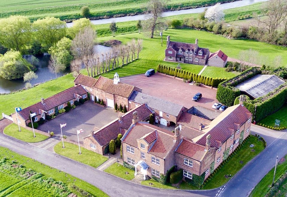 aerial view of a large brick house surrounded by green grass and trees , located in a rural area at Loftsome Bridge Hotel