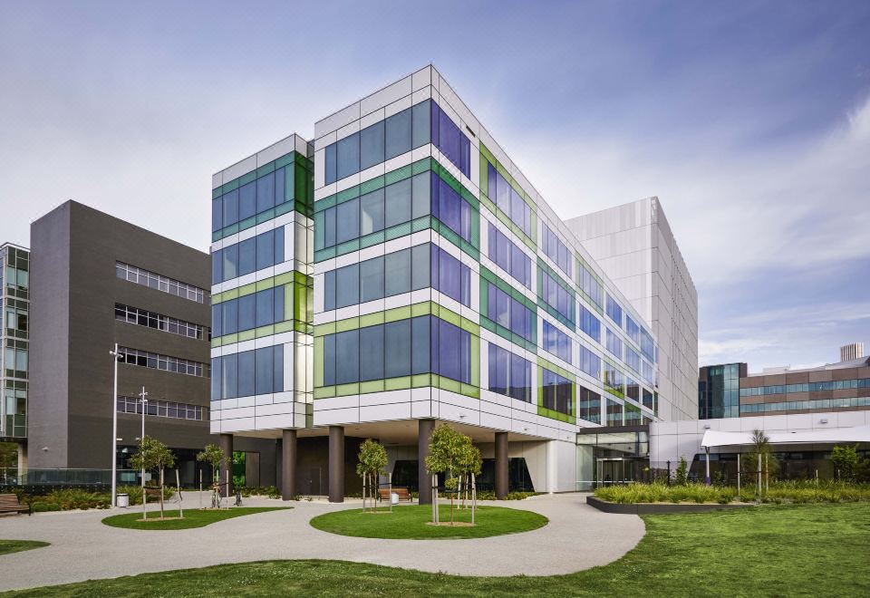 a modern , multi - level building with a glass facade and green windows , surrounded by trees and grass at The Larwill Studio Melbourne - Art Series