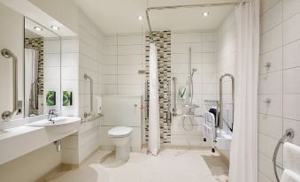 a modern bathroom with white walls , a walk - in shower , and a toilet , along with two lamps on the wall at Premier Inn Tewkesbury