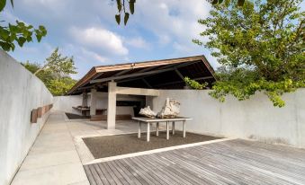 a modern building with a wooden exterior , white walls , and large windows , surrounded by trees and benches on a wooden deck at Berugo Cottage