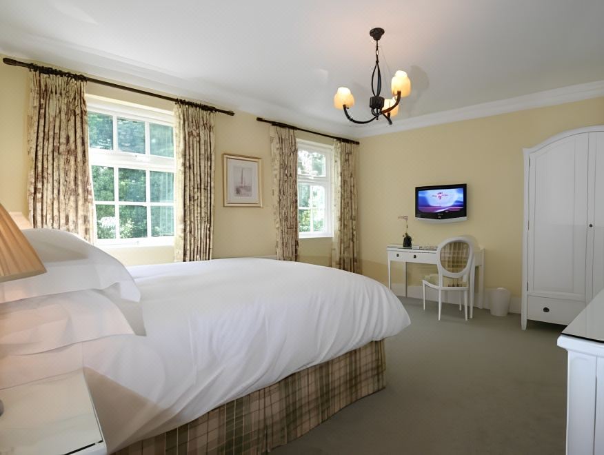a large bedroom with a king - sized bed , a television , and a chandelier hanging from the ceiling at Flynns of Termonfeckin Boutique Hotel