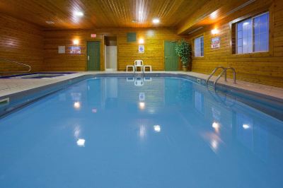 a large indoor swimming pool with blue water , surrounded by wooden walls and a ceiling with lights at Country Inn & Suites by Radisson, Watertown, SD