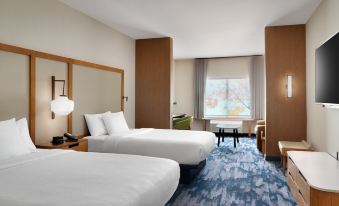 a hotel room with two beds , a window , and a blue carpeted floor , all decorated in white at Fairfield Inn & Suites Houston League City