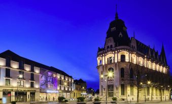 a city street at night , with a large building on the left side of the road and a traffic light in the middle of the street at Hôtel Mercure Chartres Centre Cathédrale