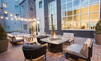 a patio area with a fire pit surrounded by various chairs and tables , creating an inviting atmosphere at Staybridge Suites Denver North - Thornton