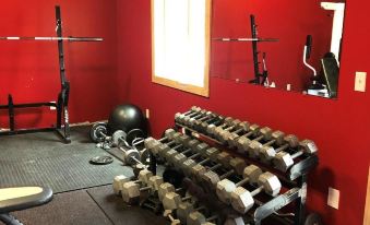 a red room with a variety of exercise equipment , including a weight bench and dumbbells at Rays Place Inn