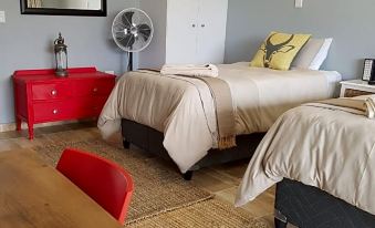 a room with two twin beds , a red dresser , and a fan on the wall at Graceland Guesthouse