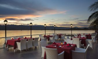 a restaurant with red and white tables and chairs is set up near the water at Swiss-Belhotel Silae Palu