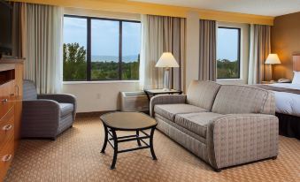 a living room with a couch , chair , and coffee table is shown with large windows at DoubleTree by Hilton Hotel Grand Junction