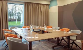 a conference room with a large table surrounded by chairs and water bottles , along with a window at Hampton by Hilton  Edinburgh Airport