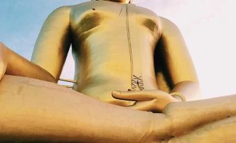 a large golden statue of buddha , surrounded by a group of people , with the sun setting in the background at Smile Resort