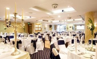 a large dining room with multiple tables covered in white tablecloths and chairs arranged for a formal event at Tara Hotel