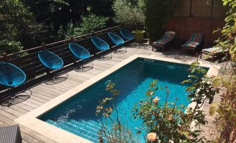 a backyard with a large pool surrounded by several lounge chairs and a wooden deck at Hôtel Restaurant Notre Dame