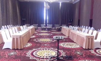 a long conference table with chairs , white tablecloths , and a chandelier in a spacious room at Java Palace Hotel
