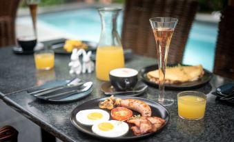 a dining table with a variety of breakfast foods , including eggs , sausage , and orange juice at Ruby Rose