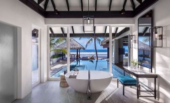 a bathroom with a bathtub and a view of the ocean through large windows at Naladhu Private Island