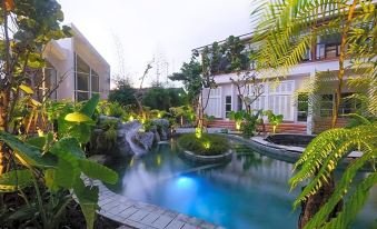 a beautiful backyard with a swimming pool , waterfall , and surrounding plants , creating a serene atmosphere at Yats Colony