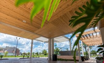 a wooden patio with a pergola , surrounded by greenery and a building in the background at Home2 Suites by Hilton Lake City