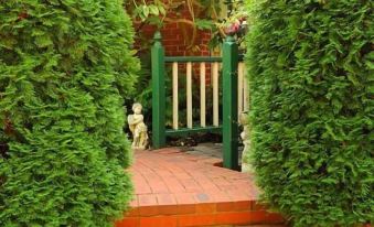 a green door is in the middle of a garden with orange stairs and bushes at Mary Cards Coach House