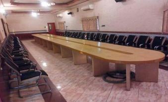 a long wooden table with black chairs and white walls in an empty room , possibly a conference room at Royal Inn