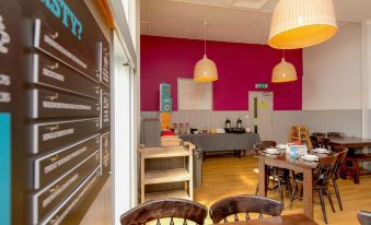 "a dining room with a wooden table , chairs , and a blackboard displaying the words "" 1 0 4 "" on it" at YHA Blaxhall - Hostel