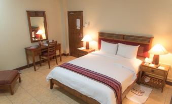 a well - arranged hotel room with a large bed , wooden furniture , and a desk area near the window at Discovery Inn